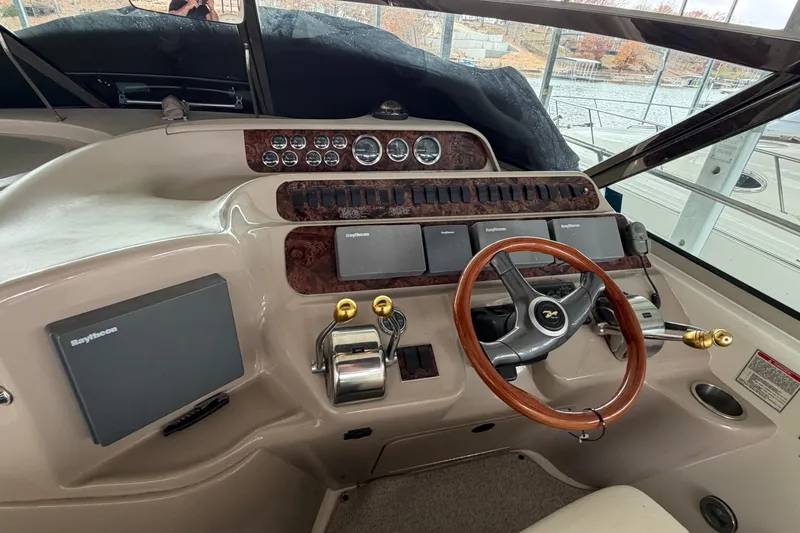 Slide: The Image of 1999 Sea Ray 400 Sundancer helm with wood steering wheel and navigation controls. - 15