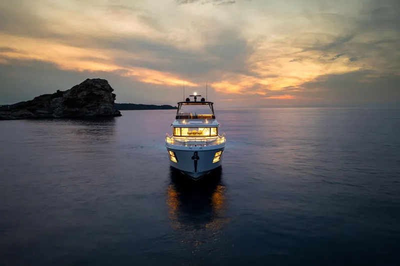 Slide: The Image of 2025 Beneteau Grand Trawler 63 at sunset on calm waters. - 13