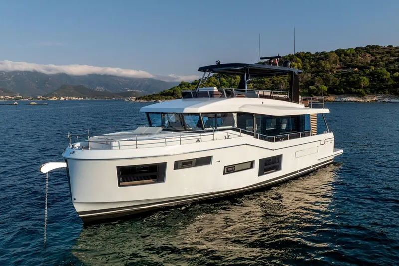 Slide: The Image of 2025 Beneteau Grand Trawler 63 yacht on serene waters, scenic coastal backdrop. - 15