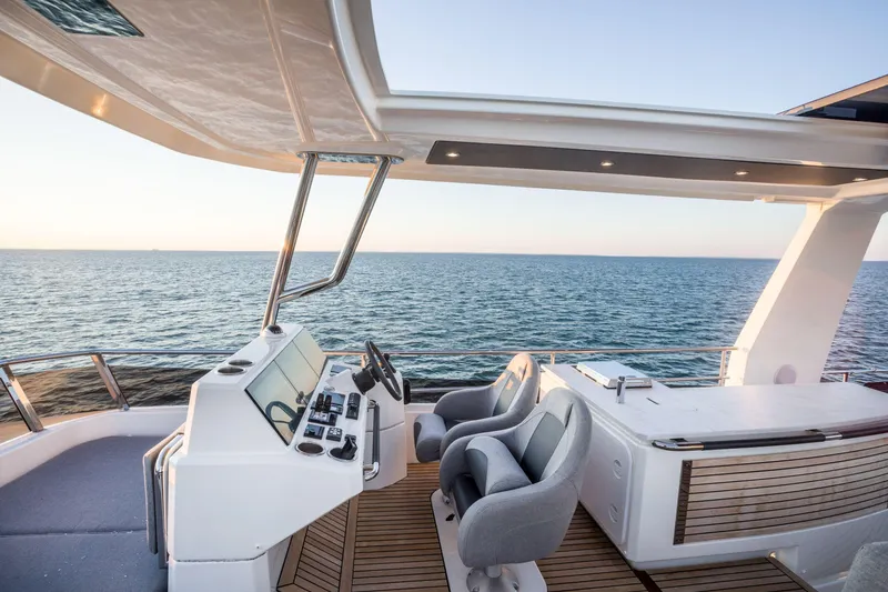 Slide: The Image of 2025 Beneteau Grand Trawler 63 helm station overlooking the ocean at sunset. - 33