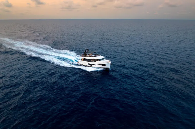 Slide: The Image of 2025 Beneteau Grand Trawler 63 cruising on open sea at sunset. - 5