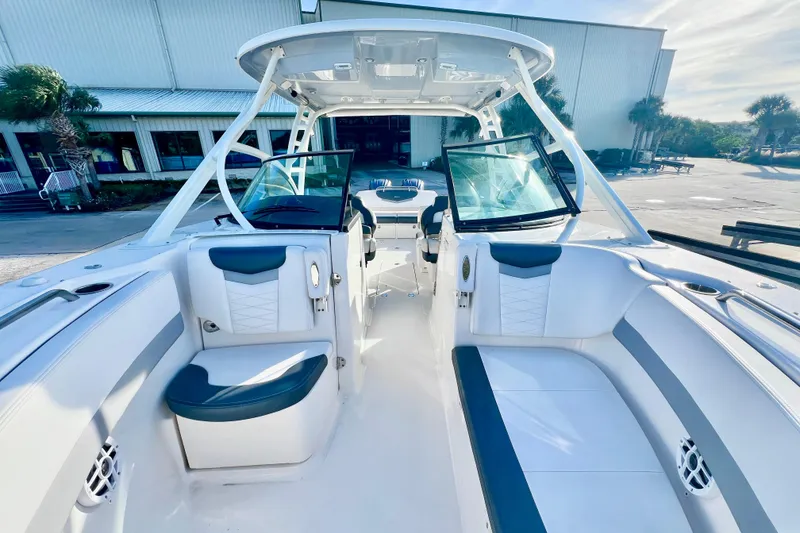 Slide: The Image of 2021 Robalo R317 Dual Console boat interior with white seating and palm trees in background. - 23