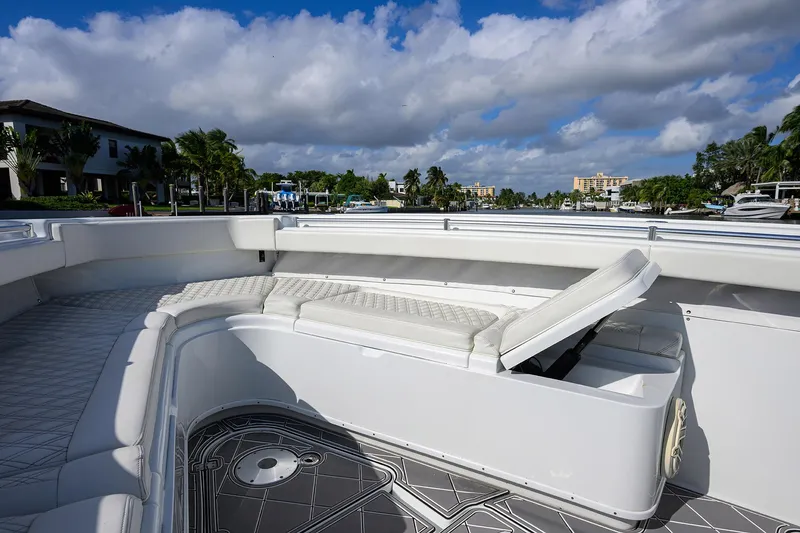 Slide: The Image of 2021 Yellowfin 42 boat with cushioned seating, docked under a partly cloudy sky. - 24