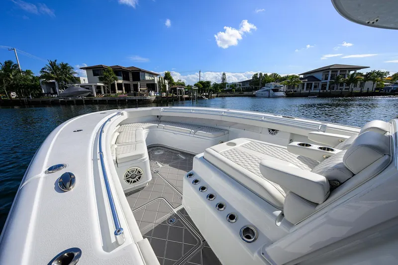 Slide: The Image of 2021 Yellowfin 42 boat with luxurious seating, docked near waterfront homes under a clear blue sky. - 27