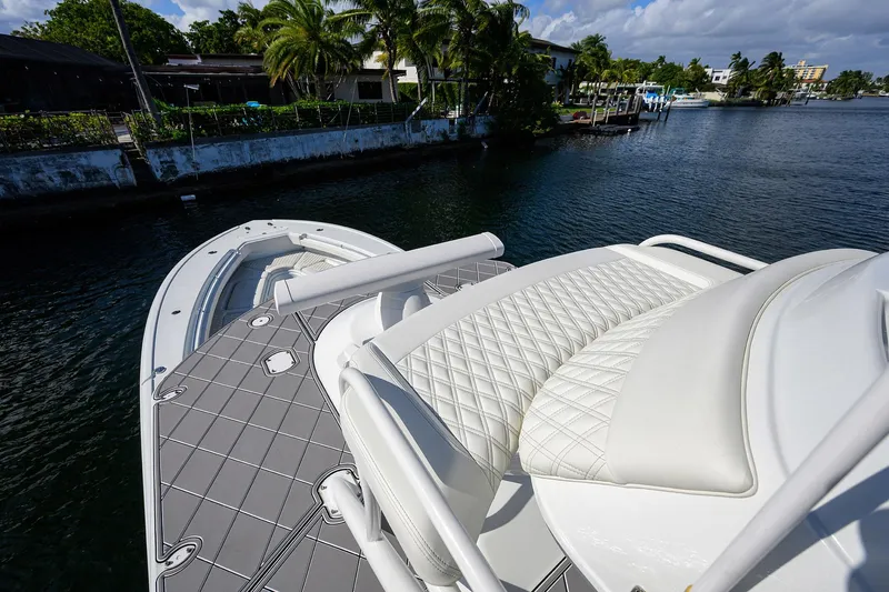 Slide: The Image of 2021 Yellowfin 42 boat with luxurious seating, docked near lush waterfront homes. - 42