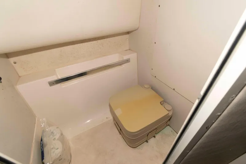 Slide: The Image of 1999 Mako 253 Walk Around boat interior with compact portable toilet. - 10