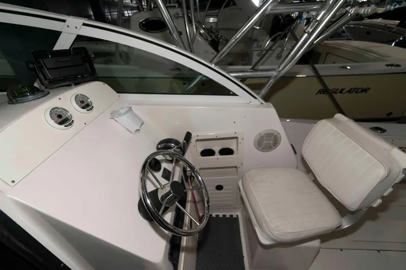 Slide: The Image of 1999 Mako 253 Walk Around boat helm with steering wheel and gauges. - 6