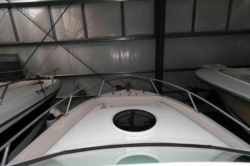 Slide: The Image of 1999 Mako 253 Walk Around boat stored indoors, showing bow and hatch. - 8