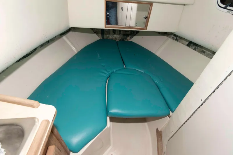 Slide: The Image of 1999 Mako 253 Walk Around cabin interior with teal cushions and compact design. - 9