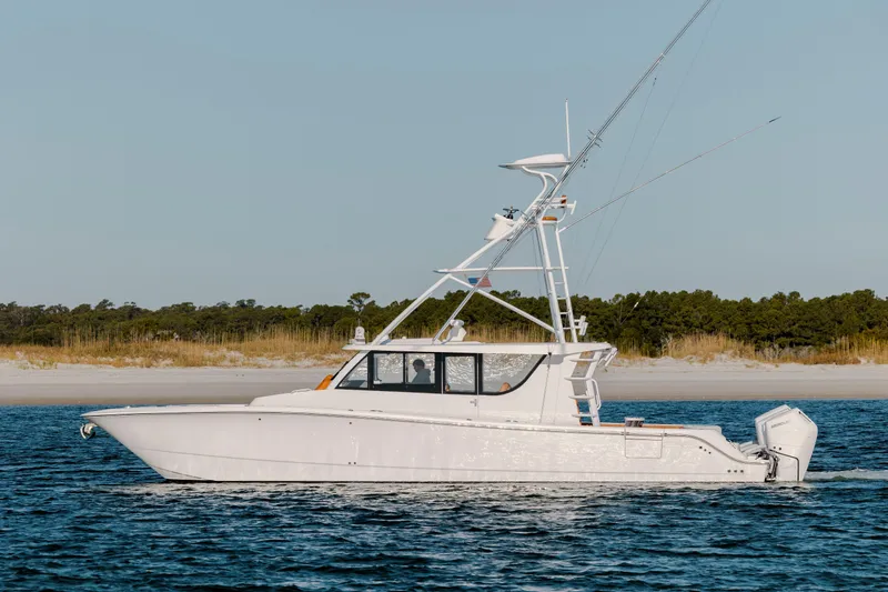 The Image of 2024 Invincible 46 Pilothouse boat cruising near sandy shoreline. - 0