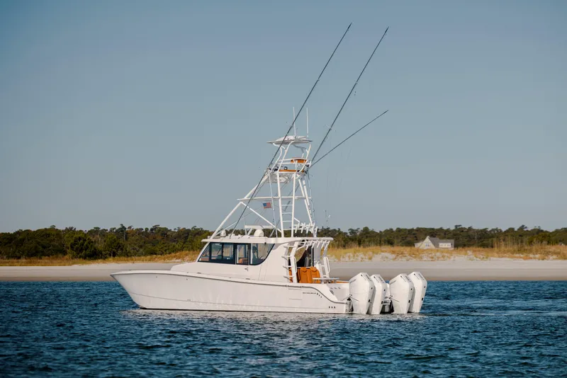 Slide: The Image of 2024 Invincible 46 Pilothouse boat cruising on calm waters near a sandy shoreline. - 2