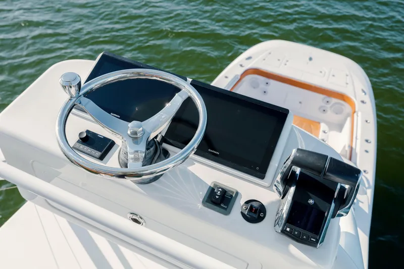Slide: The Image of 2024 Invincible 46 Pilothouse helm with modern controls and dual screens on open water. - 47