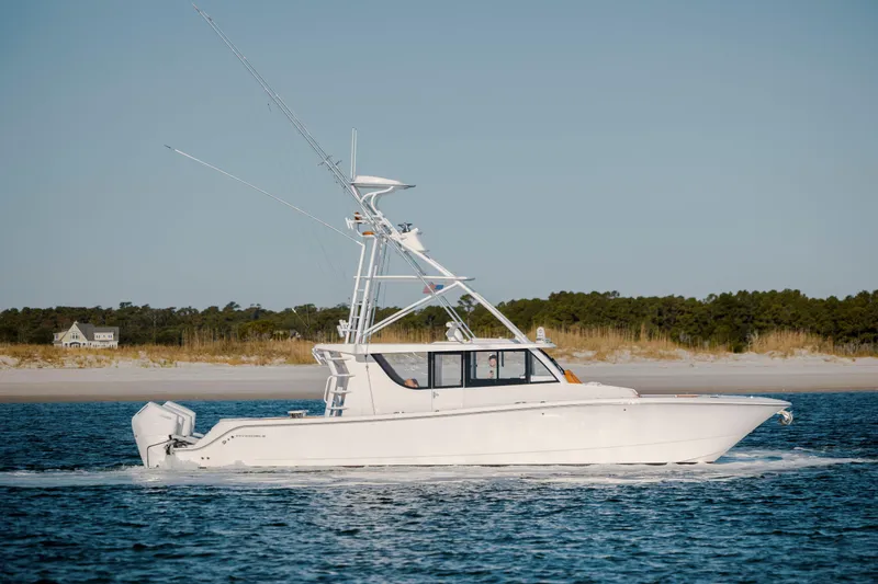 Slide: The Image of 2024 Invincible 46 Pilothouse cruising on calm waters near a sandy shoreline. - 5