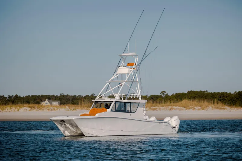 Slide: The Image of 2024 Invincible 46 Pilothouse boat cruising near a sandy shoreline. - 6