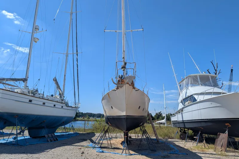 Slide: The Image of Bruce Bingham Custom 47 Steel Hull 1992 sailboat on land, flanked by other boats. - 4