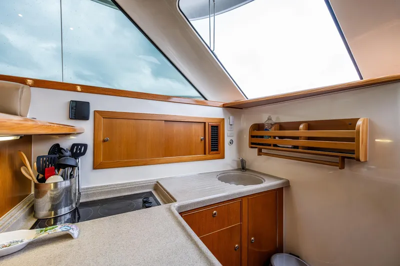 Slide: The Image of 2004 Riviera 37 Flybridge yacht kitchen with modern amenities and wooden cabinetry. - 15