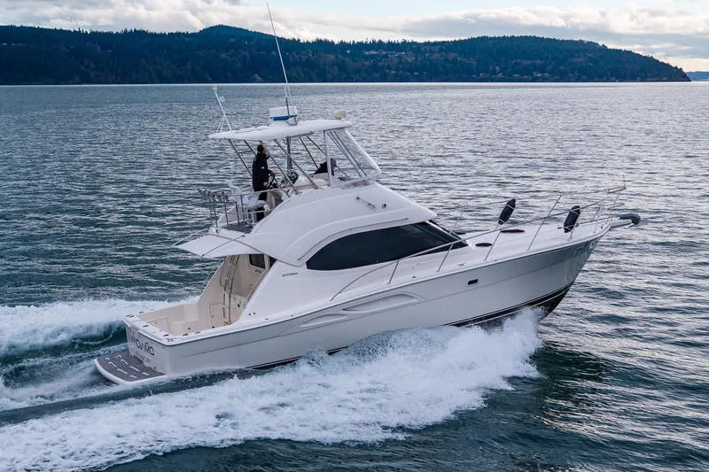 Slide: The Image of 2004 Riviera 37 Flybridge cruising on open water near forested islands. - 5