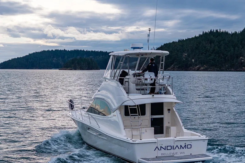 Slide: The Image of 2004 Riviera 37 Flybridge yacht cruising on scenic waters with forested shoreline. - 8