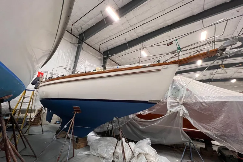 Slide: The Image of 1988 Shannon 28 sailboat in indoor storage, supported by stands, with blue hull. - 15