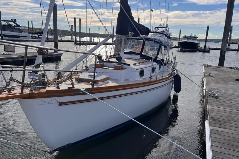 Slide: The Image of 1988 Shannon 28 sailboat docked at marina, featuring classic design and wooden accents. - 2