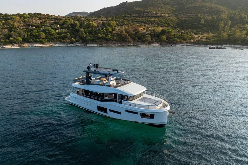 Slide: The Image of 2025 Beneteau Grand Trawler 63 yacht cruising near a scenic coastline. - 14