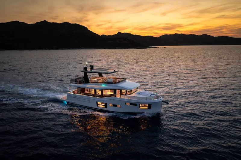 Slide: The Image of 2025 Beneteau Grand Trawler 63 cruising at sunset on calm waters. - 3