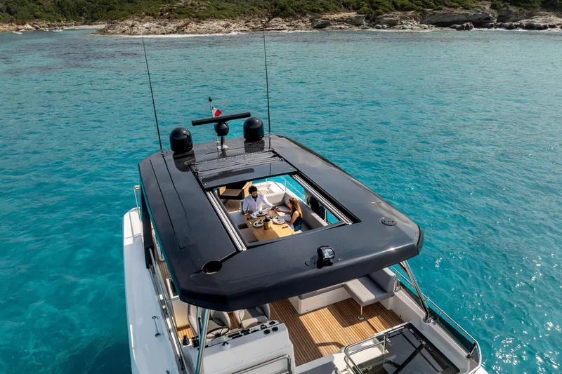 Slide: The Image of Beneteau Grand Trawler 63 (2025) cruising in clear blue waters, top deck view. - 37