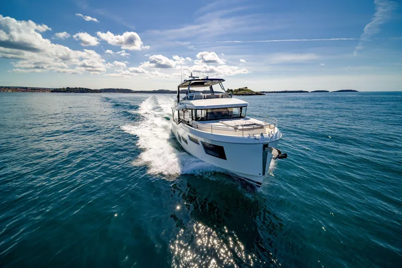Slide: The Image of 2025 Beneteau Grand Trawler 63 cruising on open sea under clear blue sky. - 4