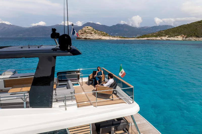 Slide: The Image of 2025 Beneteau Grand Trawler 63 cruising in turquoise waters near scenic coastline. - 41