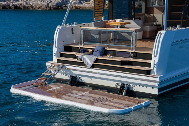 Slide: The Image of 2025 Beneteau Grand Trawler 63 yacht with open deck and swim platform on blue water. - 11