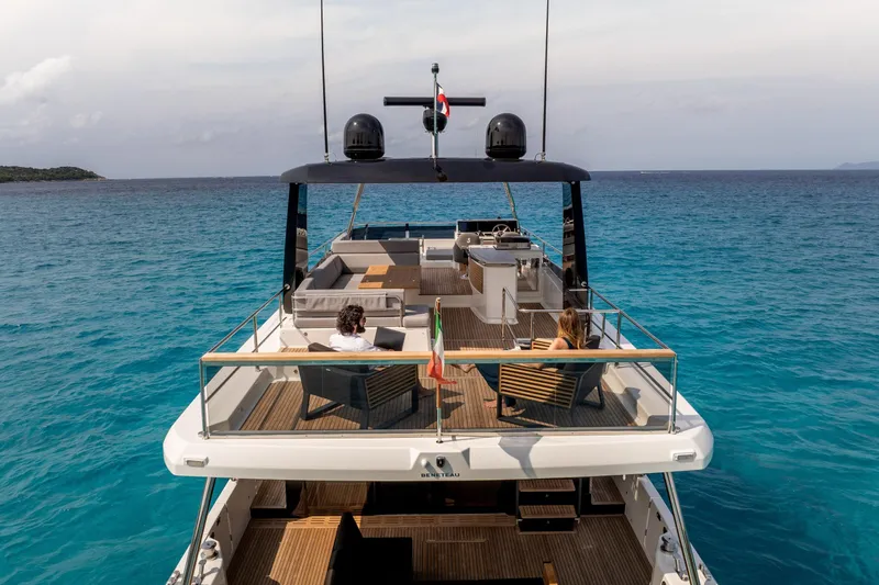 Slide: The Image of 2025 Beneteau Grand Trawler 63 yacht on clear blue water, featuring spacious deck and seating. - 42