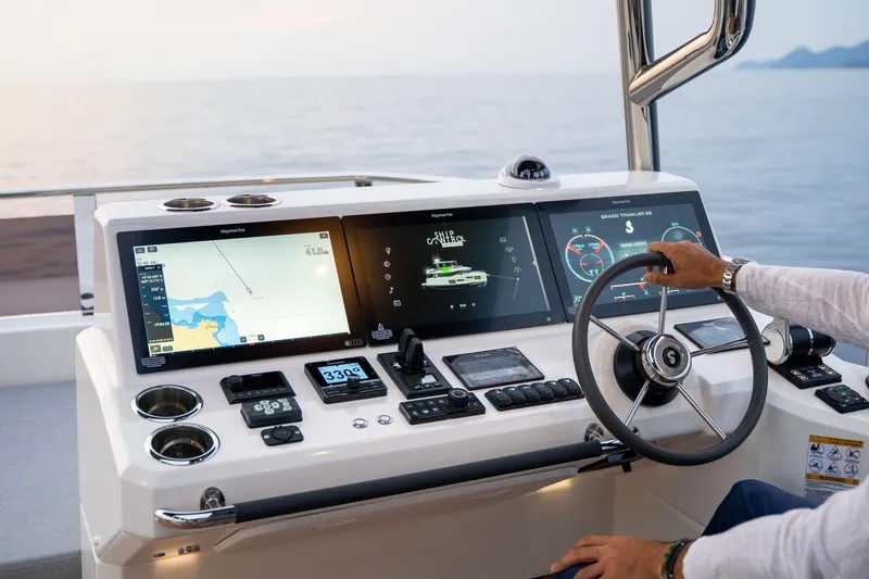 Slide: The Image of Helm of 2025 Beneteau Grand Trawler 63 with advanced navigation displays and controls. - 43
