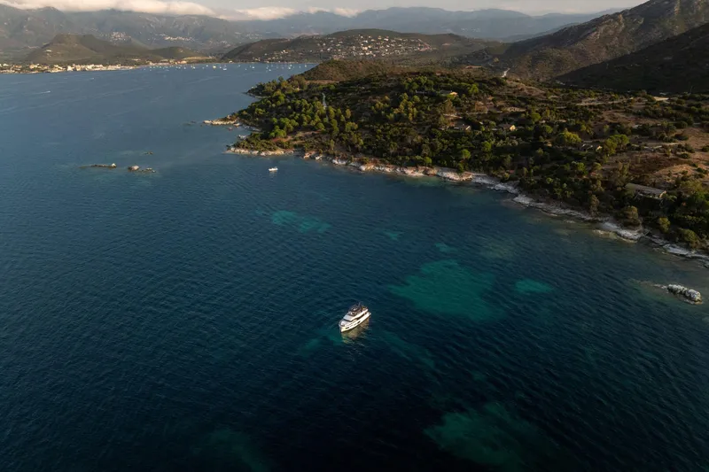 Slide: The Image of Aerial view of Beneteau Grand Trawler 63, 2025, cruising near a scenic coastline. - 45