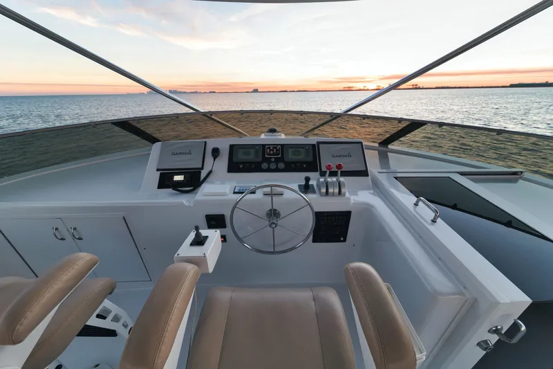 Slide: The Image of Helm of 2002 Hatteras Motor Yacht at sunset, featuring dual seats and navigational controls. - 13