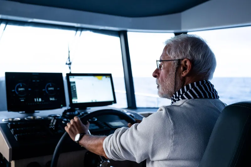 Slide: The Image of Elderly man steering 2026 Beneteau Swift Trawler 54, focused on navigation screens. - 22