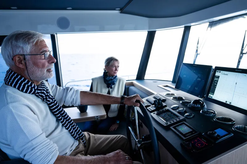 Slide: The Image of Elderly couple navigating 2026 Beneteau Swift Trawler 54, modern cockpit, ocean view. - 23