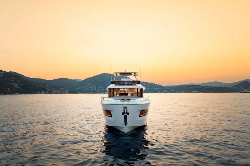 Slide: The Image of 2026 Beneteau Swift Trawler 54 on serene water at sunset, surrounded by hills. - 3
