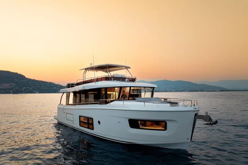 Slide: The Image of 2026 Beneteau Swift Trawler 54 yacht at sunset on calm waters. - 5