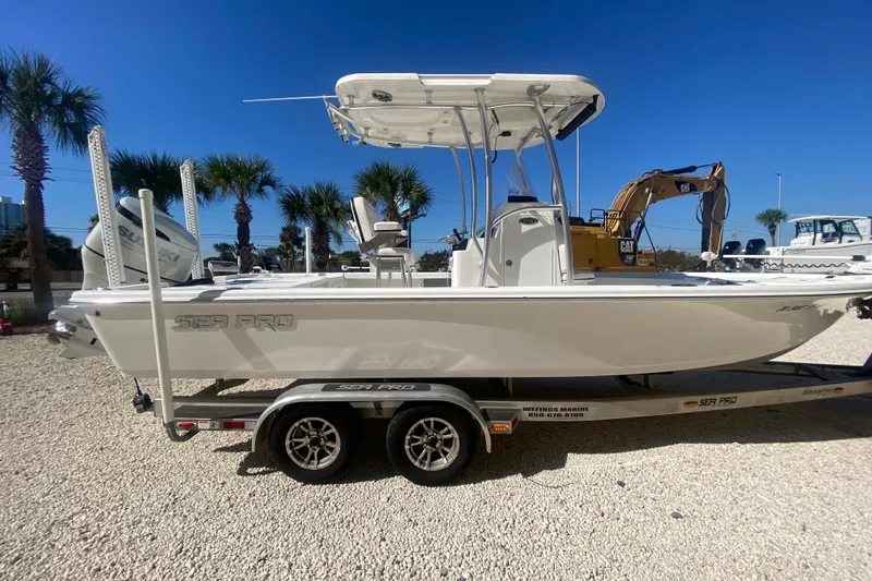 Slide: The Image of 2021 Sea Pro 248 Bay boat on trailer, parked outdoors under clear blue sky. - 2