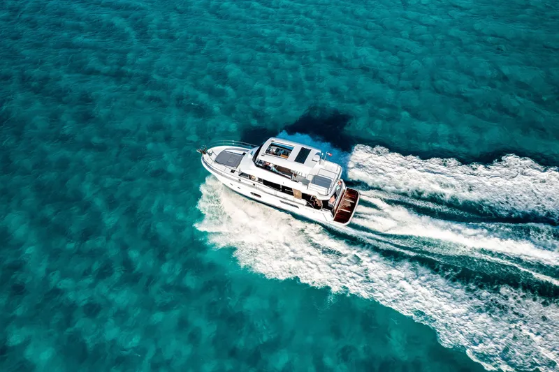 Slide: The Image of 2026 Beneteau Swift Trawler 48 cruising on clear turquoise waters. - 17
