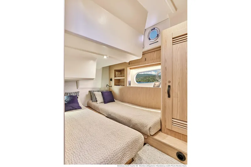 Slide: The Image of Interior of 2026 Beneteau Swift Trawler 48, featuring twin beds and modern wood finishes. - 29