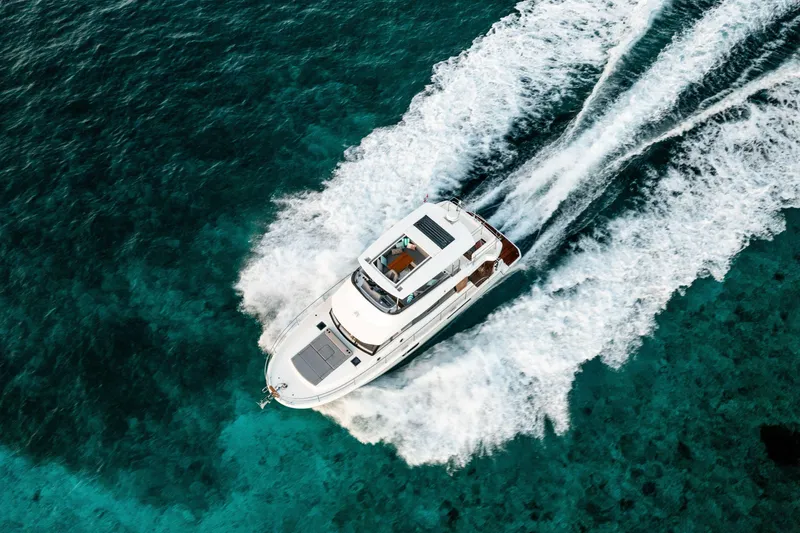 Slide: The Image of 2026 Beneteau Swift Trawler 48 cruising on clear turquoise waters, aerial view. - 4