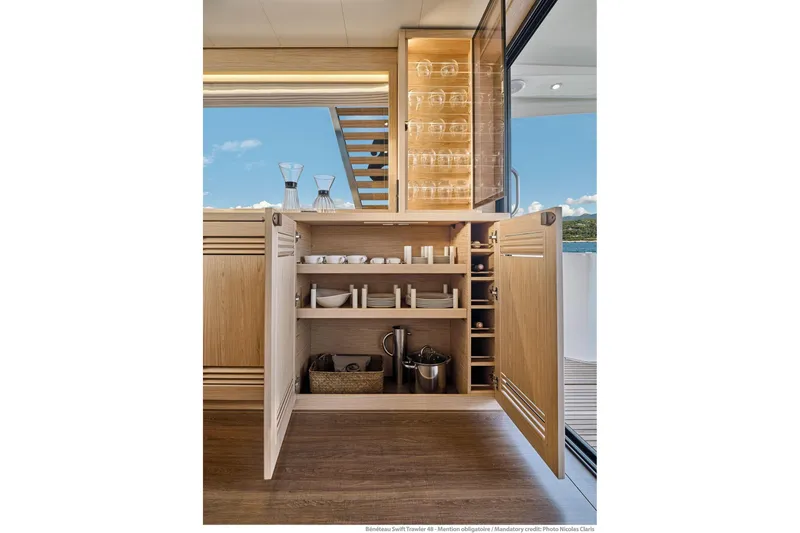 Slide: The Image of Luxurious interior of 2026 Beneteau Swift Trawler 48, featuring elegant wooden cabinetry and glassware. - 47