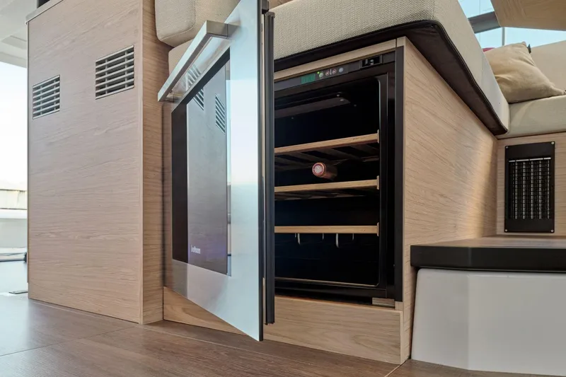 Slide: The Image of 2026 Beneteau Swift Trawler 48 interior with open wine cooler and wooden finish. - 48