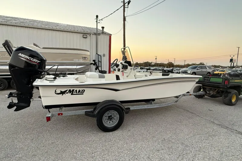 Slide: The Image of 2023 Mako Pro Skiff 15 CC boat with Mercury engine on trailer at sunset. - 15