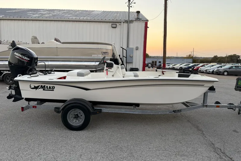 Slide: The Image of 2023 Mako Pro Skiff 15 CC boat on trailer, parked outdoors at sunset. - 16