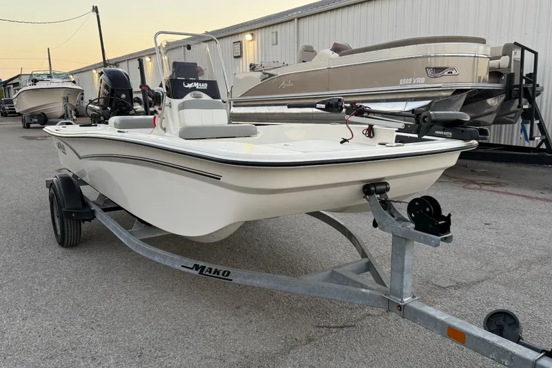 Slide: The Image of 2023 Mako Pro Skiff 15 CC boat on trailer, parked outdoors near a building. - 18