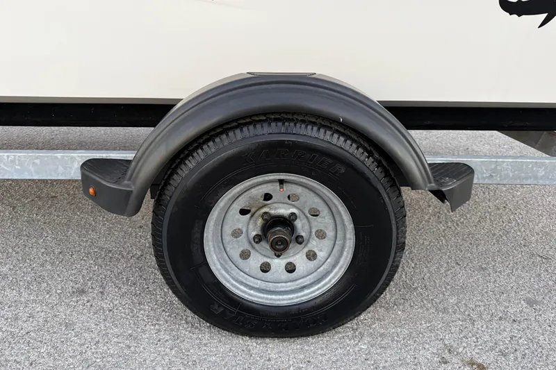 Slide: The Image of Close-up of a 2023 Mako Pro Skiff 15 CC trailer tire on asphalt. - 48