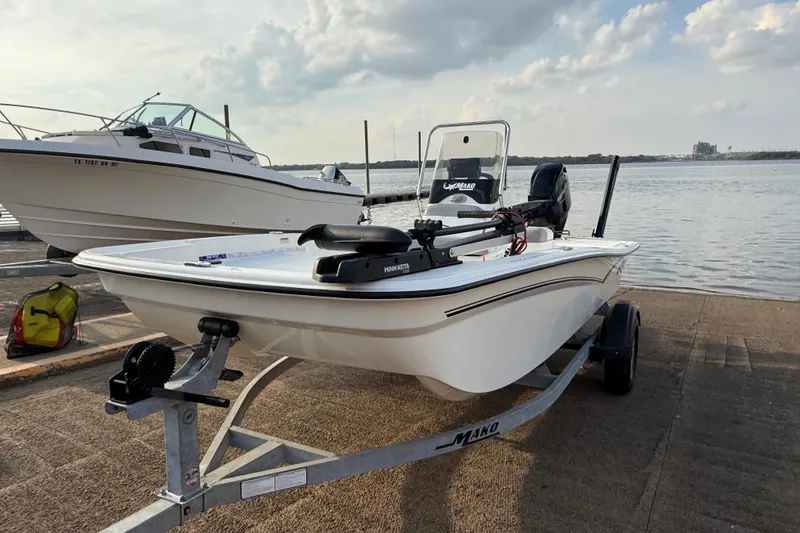 Slide: The Image of 2023 Mako Pro Skiff 15 CC boat with Mercury engine on trailer at sunset. - 54
