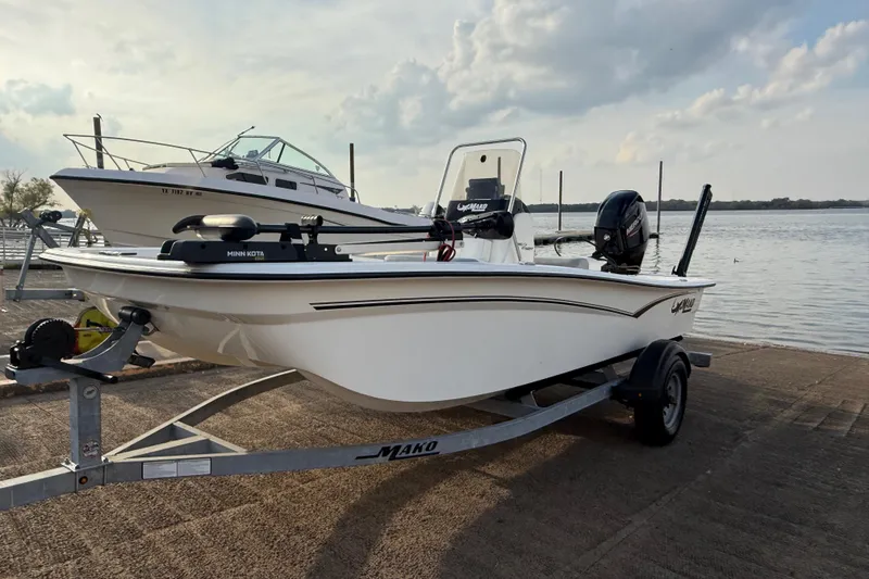 Slide: The Image of 2023 Mako Pro Skiff 15 CC boat on trailer by the water. - 55